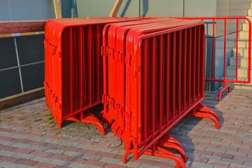 A stack of portable metal traffic barriers of red color on the stadium.