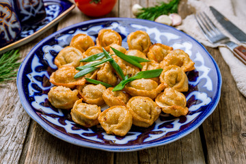 Dumplings chuchvara fried Uzbek cuisine on wooden background