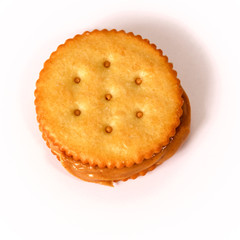 Natural organic peanut butter fills and oozes out of this sandwich made with golden round crackers on white background from above
