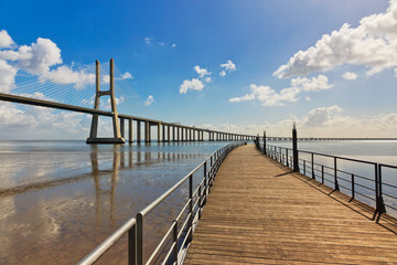 Fototapeta na wymiar Wooden walkway with view on Vasco da Gama bridge