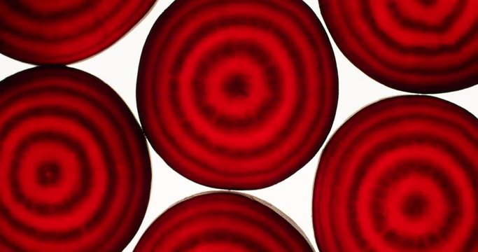 Raw beetroot slices rotating on a bright white background. Close up top view, shot on RED 6K camera