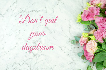 White marble texture background with pink flowers border frame and inspirational, don't quit your daydream, text greeting.