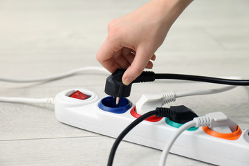 Woman inserting power plug into extension cord on floor, closeup. Electrician's professional equipment