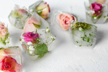 Ice cubes with flowers on white background, closeup