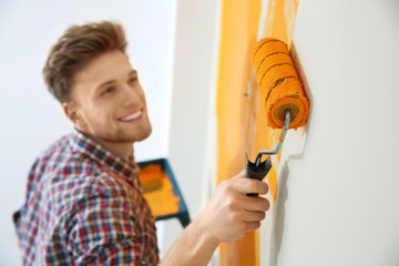 Happy young man painting wall indoors. Home repair