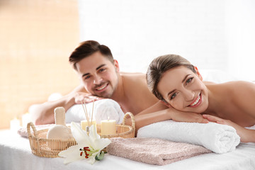 Obraz na płótnie Canvas Young couple with spa essentials in wellness center