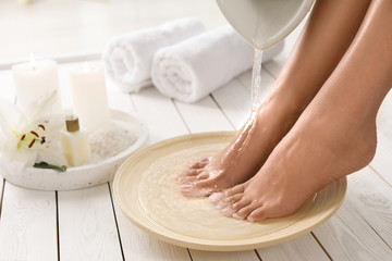 Closeup view of woman filling dish with water for foot bath indoors. Spa treatment