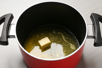 Pot with melting butter on grey table, closeup