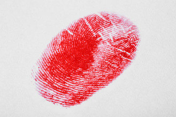 Red fingerprint on white background. Friction ridge pattern