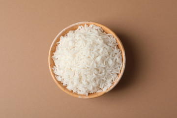 Bowl of tasty cooked rice on color background, top view