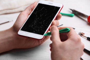 Technician fixing mobile phone at table, closeup. Device repair service
