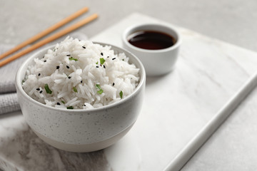 Bowl of tasty cooked rice served on table. Space for text