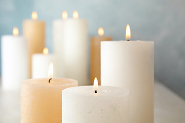 Fototapeta na wymiar Burning candles on table against color background, closeup