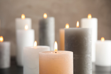 Fototapeta na wymiar Burning candles on table against color background, closeup