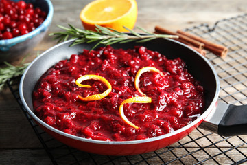 Tasty cranberry sauce with citrus zest in pan on table