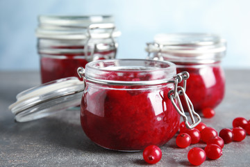 Glass jars with cranberry sauce on table, closeup
