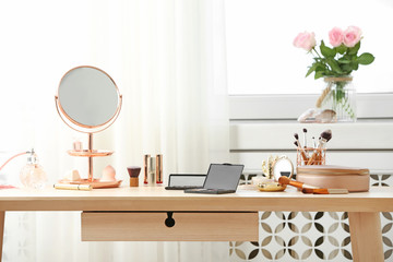 Dressing table with different makeup products and accessories in room interior - obrazy, fototapety, plakaty