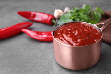 Pan of hot chili sauce and ingredients on table. Space for text
