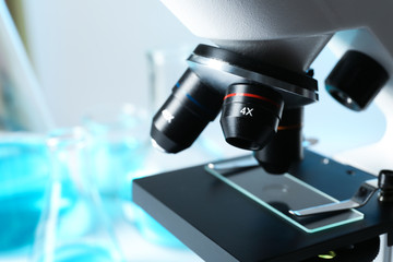 Closeup view of modern microscope with different lenses, space for text. Chemical research
