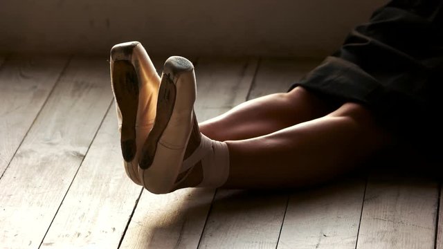 Beautiful legs of ballerina sitting on the floor. Slim legs of ballet dancer resting in ballet class.