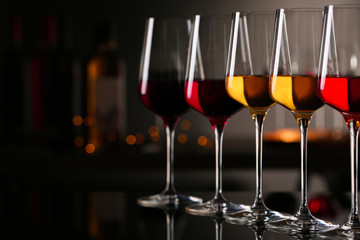 Row of glasses with different wines on bar counter against blurred background. Space for text