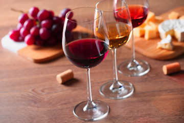 Glasses with different wines and appetizers on wooden table