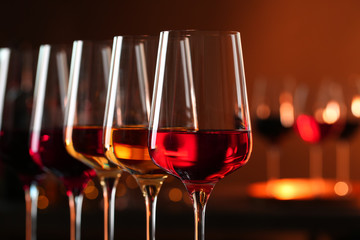 Row of glasses with different wines against blurred background, closeup. Space for text
