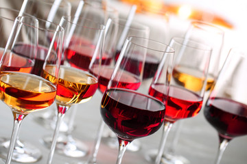 Glasses with different wines on blurred background, closeup