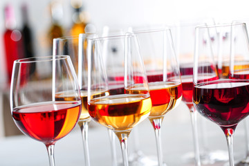 Glasses with different wines on blurred background, closeup