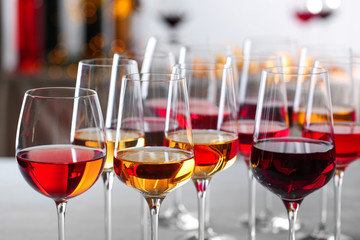 Glasses with different wines on blurred background, closeup