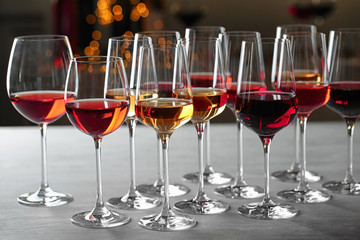 Group of glasses with different wines on table against blurred background