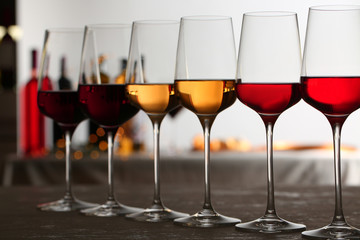 Row of glasses with different wines on table against blurred background