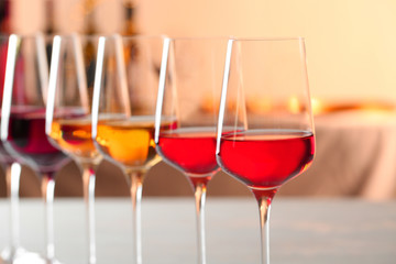 Row of glasses with different wines against blurred background, closeup