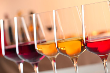 Row of glasses with different wines against blurred background, closeup