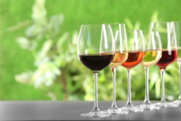 Row of glasses with different wines on grey table against blurred background. Space for text