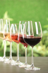 Row of glasses with different wines on grey table against blurred background