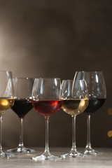 Glasses with different wines on table against dark background. Space for text