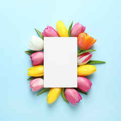 Beautiful composition with spring flowers and blank card on color background, top view. Space for text