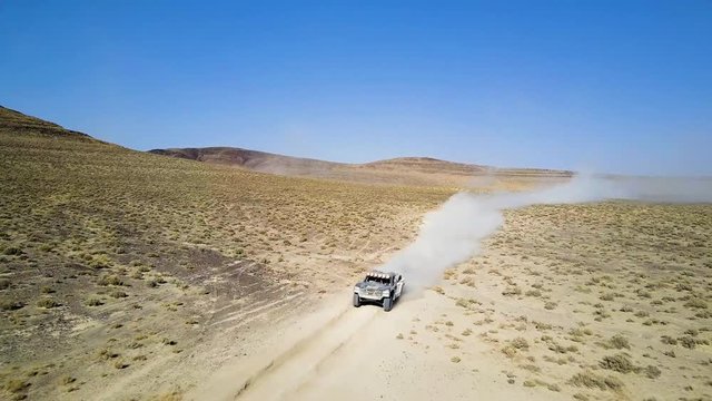 Aerial pull out of two off road vehicles driving towards the camera during a desert race in Fallon, Nevada.