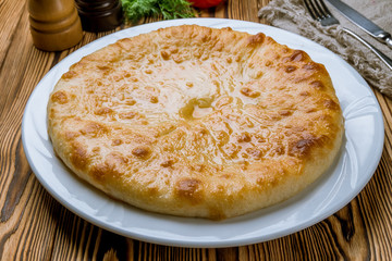 Ossetian pie with cheese on white plate