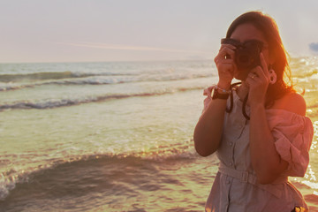 Young women are taking pictures in the sea.along the sand beaches flashes summer sun
