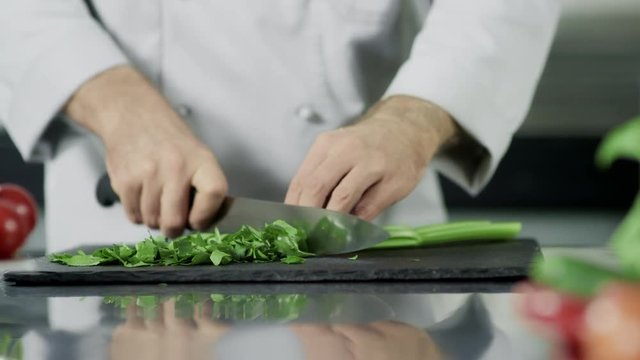 Chef hands cutting celeriac at kitchen. Closeup chef hands cooking greenery.