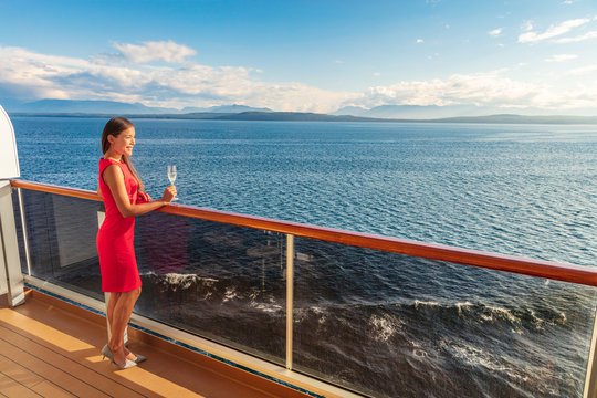 Cruise luxury travel lifestyle woman on fancy Europe vacation. Asian elegant lady drinking champagne glass watching sunset on private balcony deck.
