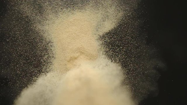 SLOW MOTION: White garlic powder pouring onto a black table