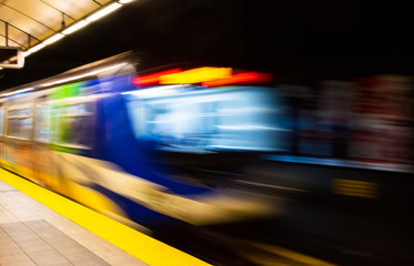 Colorful abstract with motion blur of subway train exiting station platform.