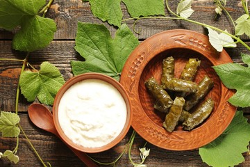 dolma- stuffed grape leaves with rice and meat. dish of Caucasian cuisine. served with fermented milk yogurt sauce. top view. cuisine of the North Caucasus. country style. clay dishes