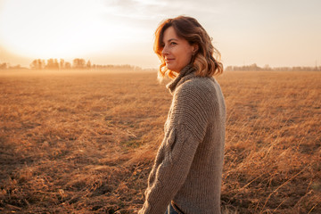 Portrait of a beautiful young model in warm clothes enjoy day, on background field in  sunny autumn...