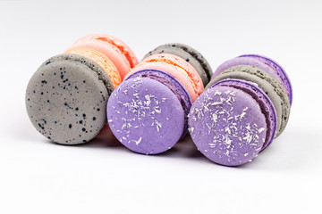 French purple, grey and pink macarons or macaroons aligned in closeup side view.