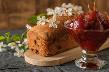 Homemade cake decorated with cherry flowers and Apple jam on the table.