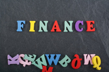 FINANCE word on black board background composed from colorful abc alphabet block wooden letters, copy space for ad text. Learning english concept.